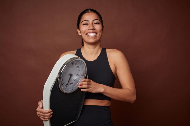 Young fitness woman measuring progress with a scale for healthy living