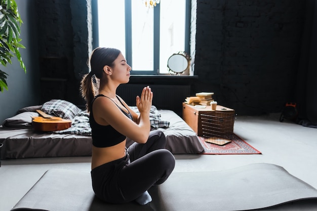 Young fitness woman meditate, doing yoga indoors at home near the bed