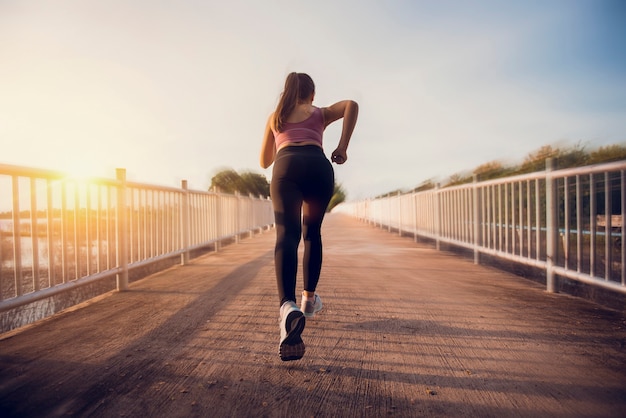 Young fitness woman runner athlete running on the road at sunset.