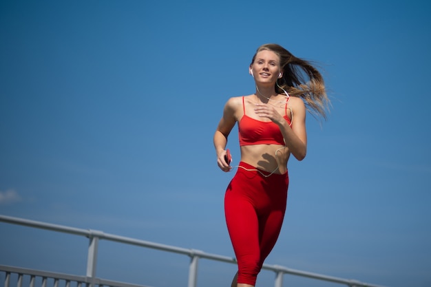 Young fitness woman running on sky backround. The concept of a healthy lifestyle