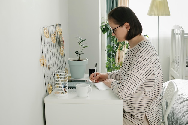 Young focused woman in striped sweater working at home