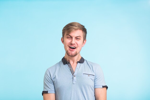 Young fool guy making grimace isolated on blue