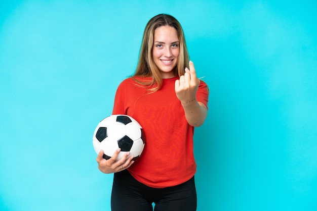 Young football player woman isolated on blue background doing coming gesture