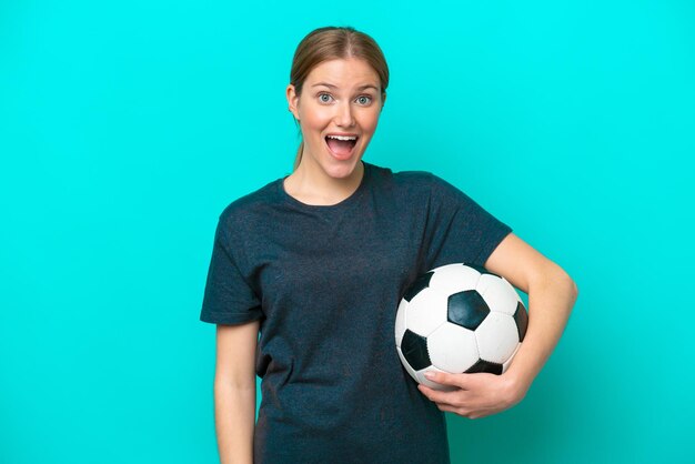 Young football player woman isolated on blue background with surprise facial expression