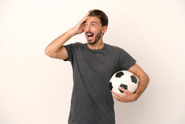 Young football player woman isolated on white background doing surprise gesture while looking to the side