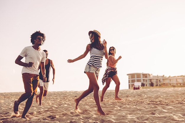 Young and free. Group of young cheerful people running along the beach and looking happy