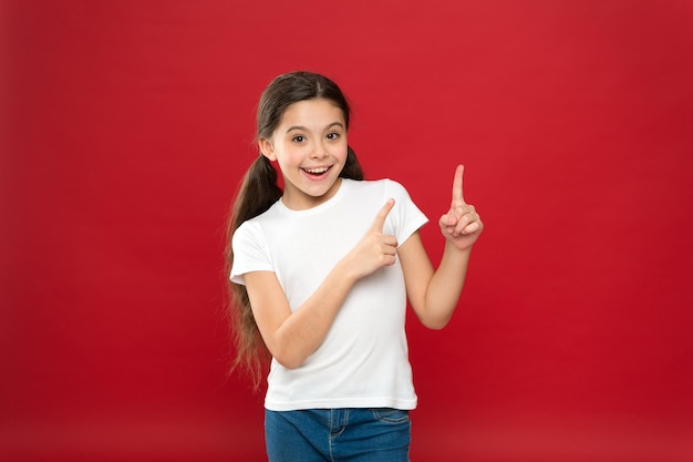 Young and free Happy child girl with long hair on red background Happiness and joy Positive emotions Child care and upbringing Kid smiling cute face live carefree happy life Enjoy every moment