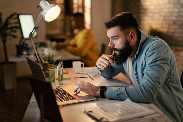 Young freelance worker using laptop while working late in the office