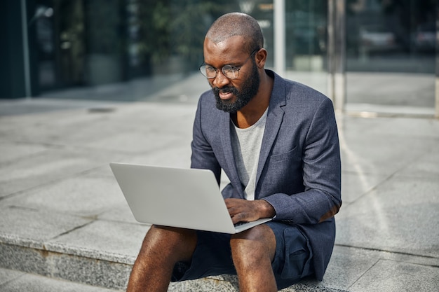 Young freelancer keeping smile on his face while answering on email