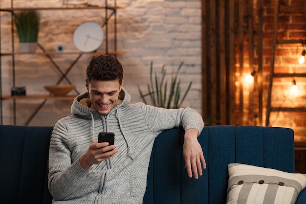 Young freelancer using smartphone and smiling.