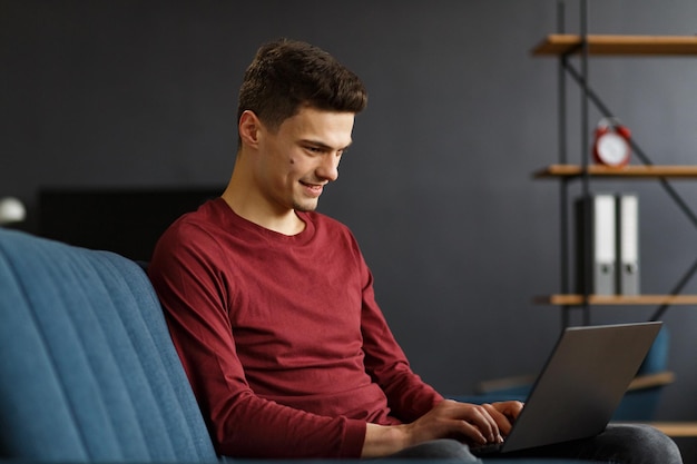 Young freelancer working in home with laptop texting messages