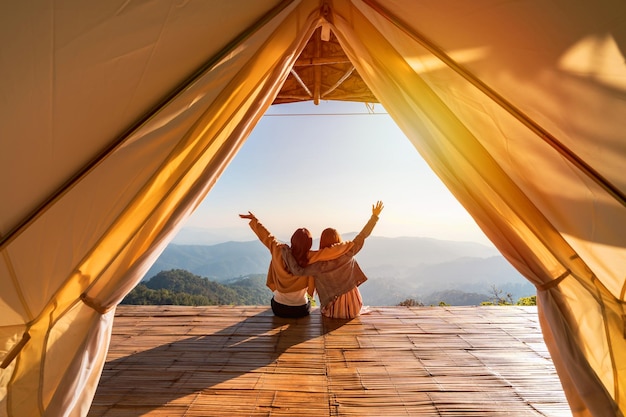 Young friend looking beautiful landscape at sunset and camping on mountain Adventure travels lifestyle concept