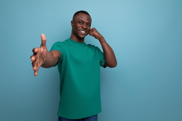 Young friendly handsome african guy with short haircut dressed in a basic tshirt smiling against the