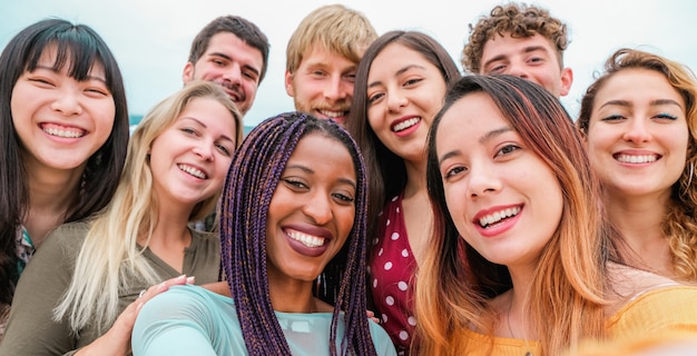 Young friends from diverse cultures and races taking photo making happy faces - Youth, millennial generation and friendship concept with students people having fun together - Focus on close-up girls