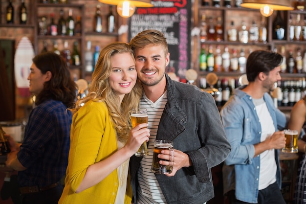 Young friends holding beer glasses in pub