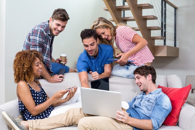 Young friends looking in laptop while sitting on sofa