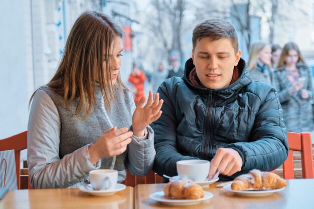 Young friends man and woman talking in outdoor cafe