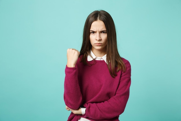 Young fun sad severe upset perplexed disturb brunette woman girl clenching fist posing isolated on blue wall background studio portrait. People sincere emotions lifestyle concept. Mock up copy space.