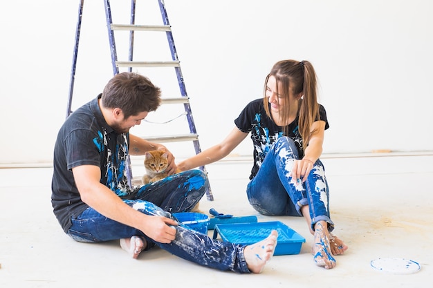 Young funny couple with cat doing renovation in new apartment.