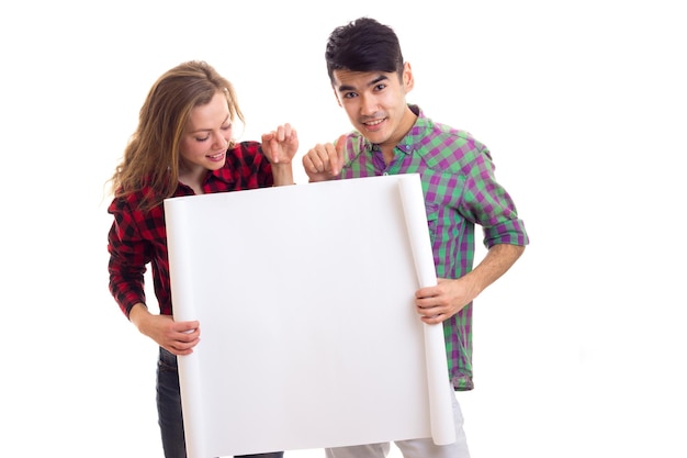 Young funny woman with young handsome man with dark hair in plaid shirts holding white placard