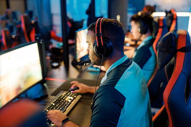 Young gamers in headsets playing in video game club