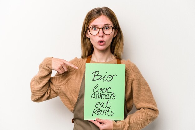 Photo young gardener woman holding a bio placard isolated on white background pointing to the side