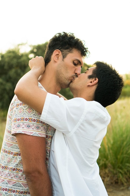 A young gay couple kissing Young loving couple in the countryside Two boyfriends on summer