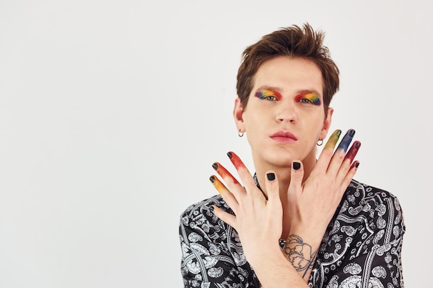 Young gay man is standing in the studio and posing for a camera Gesturing and doing facial expressions