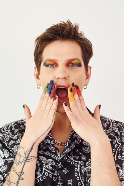 Young gay man is standing in the studio and posing for a camera Gesturing and doing facial expressions