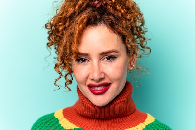 Young ginger caucasian woman isolated on blue background