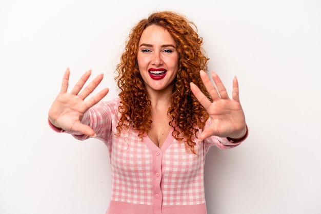 Young ginger caucasian woman isolated on white background showing number ten with hands