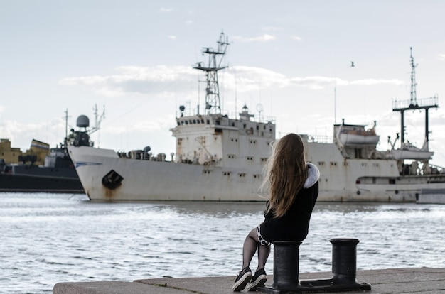 Young girl back view looking at ships. Woman dreaming about sea travel