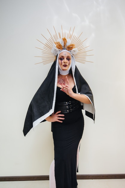 A young girl in a beautiful festive makeup and a scary nun costume for the Halloween holiday. Happy Halloween concept.