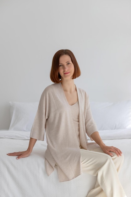 A young girl in beige clothes sits in a white cosmetology room. High quality photo