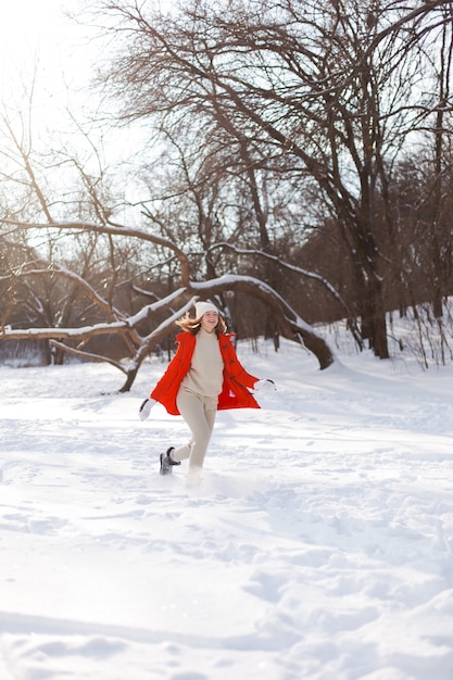 A young girl, blonde, in a sweater, a hat and an orange jacket, against the backdrop of the winter landscape. Snow and frost, the concept of Christmas.