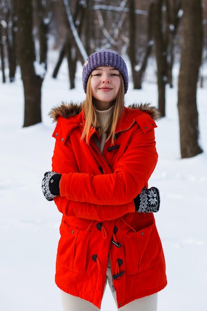 A young girl, blonde, in a sweater, a hat and an orange jacket, against the backdrop of the winter landscape. Snow and frost, the concept of Christmas.