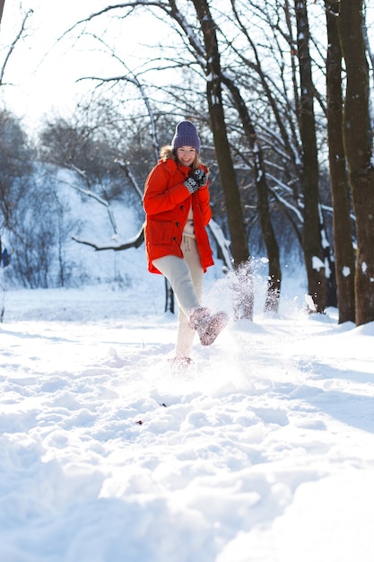 A young girl, blonde, in a sweater, a hat and an orange jacket, against the backdrop of the winter landscape. Snow and frost, the concept of Christmas.