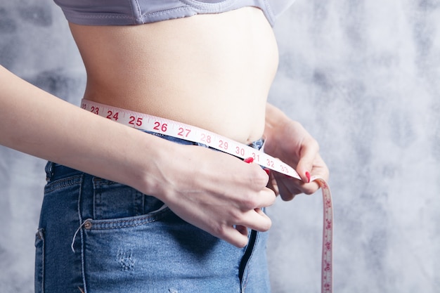 Young girl in bras measures belly with tape