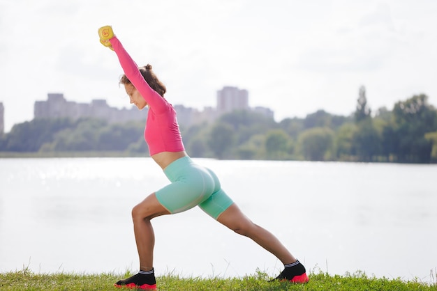 A young girl in bright clothes goes in for sports in a park in nature