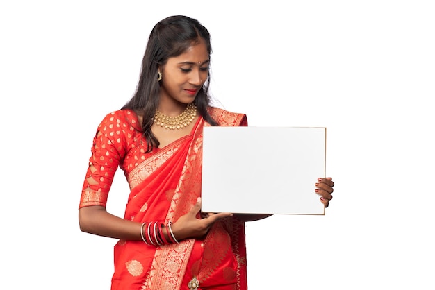 A young girl or businesswoman wearing a saree and holding a signboard in her hands on a white background