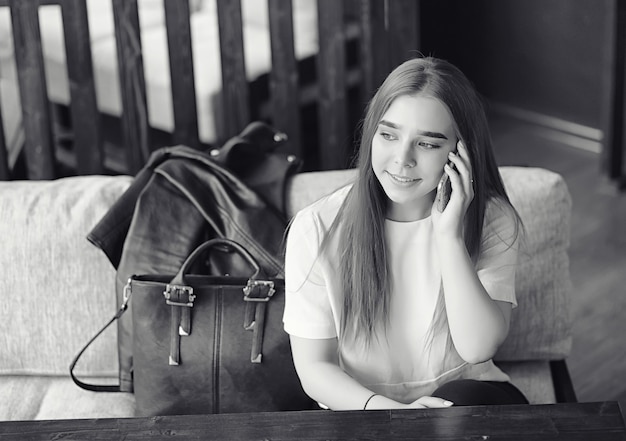 Young girl in a cafe. The girl is sitting on the couch and talking on the phone.