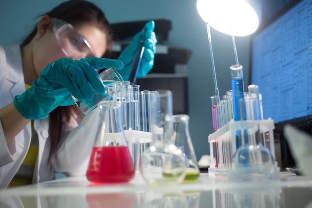 Young girl carries chemical reactions in test tubes in chemistry lab