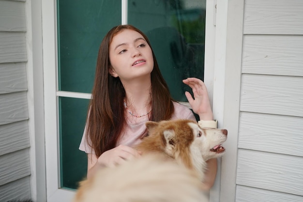 Young girl in casual clothes hugging golden retriever while sitting on floor