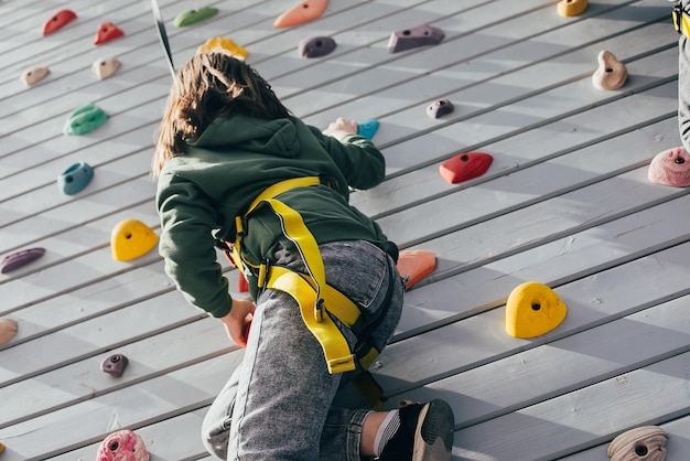 Young girl climbing on the wall View from the back Children's leisure Sport concept