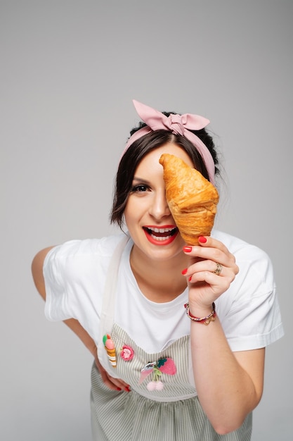 Young girl confectioner holding fresh tasty bun in hands