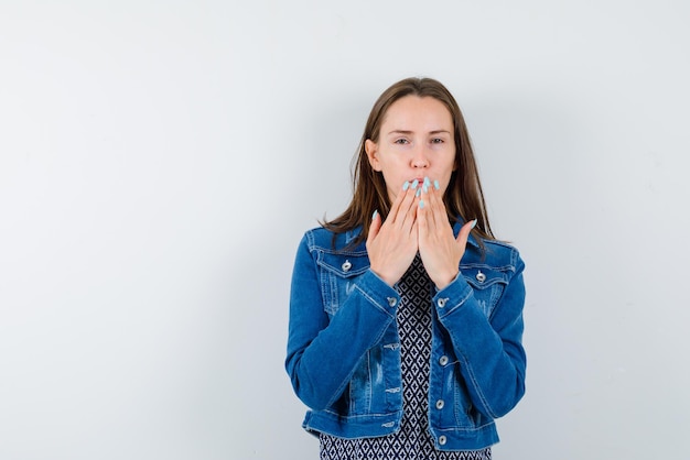 Young girl covering her mouth with hands on white background