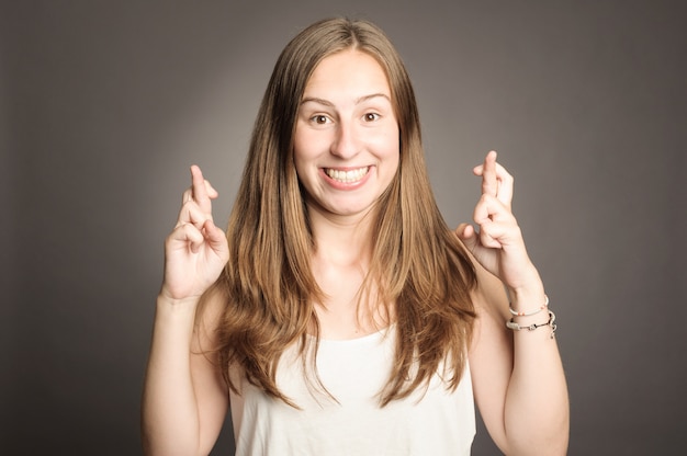 Young girl crossing fingers on gray