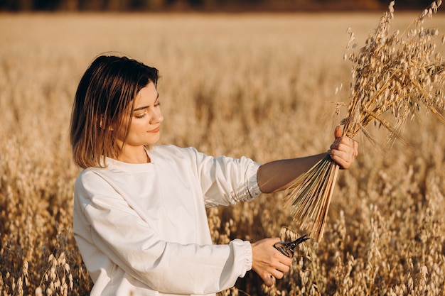 A young girl cuts the ears of oats with her hands.