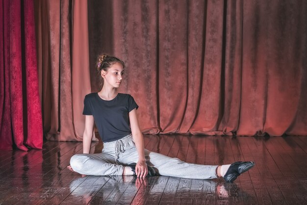 A young girl dancer practicing dance moves on stage.