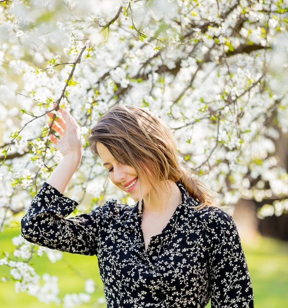 Photo young girl in dark dress stay near a flowering tree